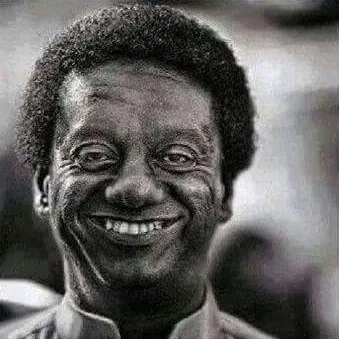 Người đàn ông da màu bật nụ cười rạng rỡ giữa đám bạn thân.